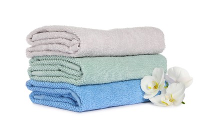 Photo of Stack of clean soft towels with orchids isolated on white
