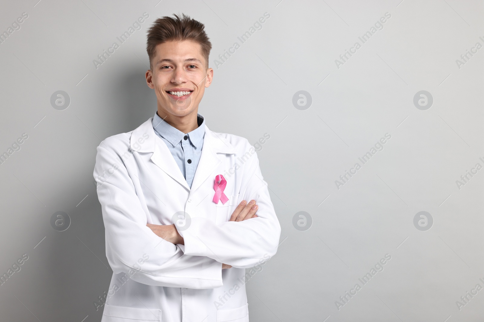 Photo of Mammologist with pink ribbon on light grey background, space for text. Breast cancer awareness