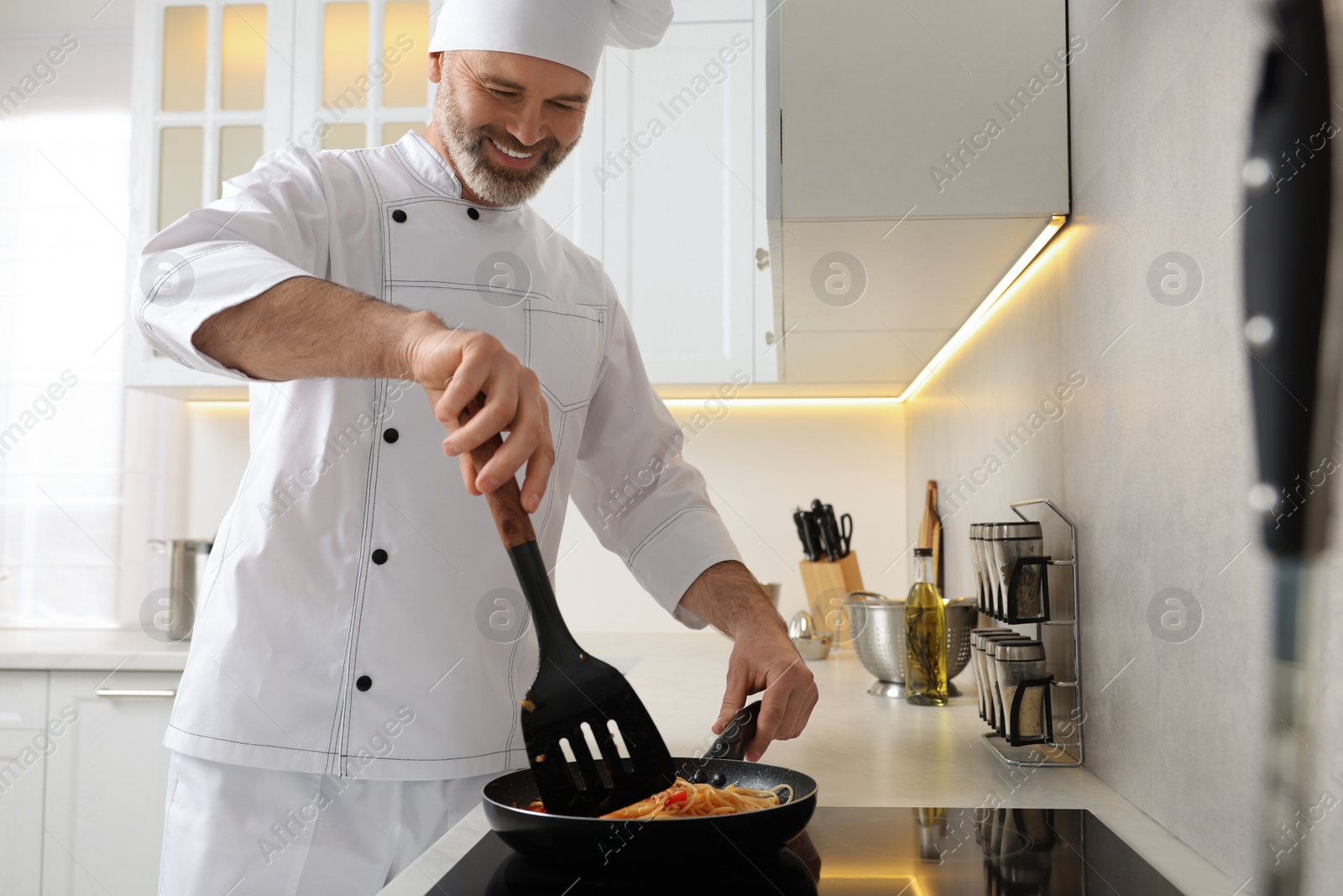 Photo of Professional chef cooking delicious pasta in kitchen