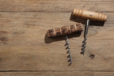 Photo of Different corkscrews on wooden table, flat lay. Space for text