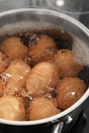 Cooking chicken eggs in pot on electric stove, closeup view