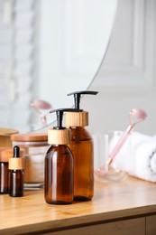 Photo of Bottles with dispenser caps and cosmetic products on wooden table indoors, closeup