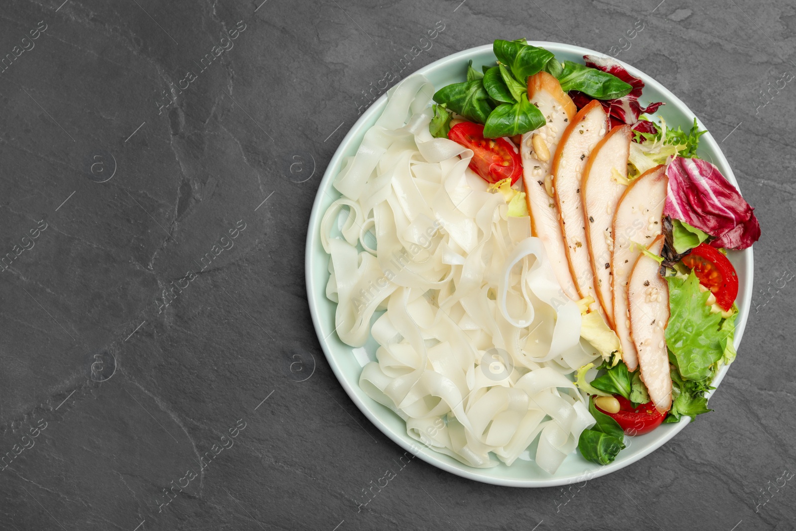 Photo of Tasty cooked rice noodles with chicken and vegetables on black table, top view