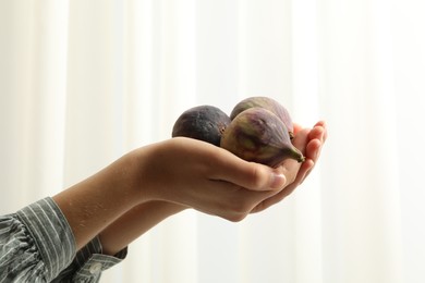 Photo of Woman holding tasty raw figs on light background, closeup