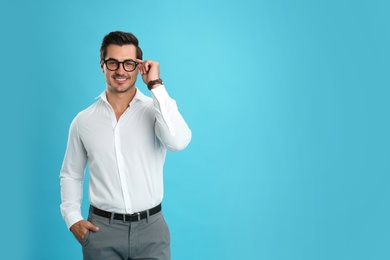 Photo of Young man with glasses on light blue background. Space for text