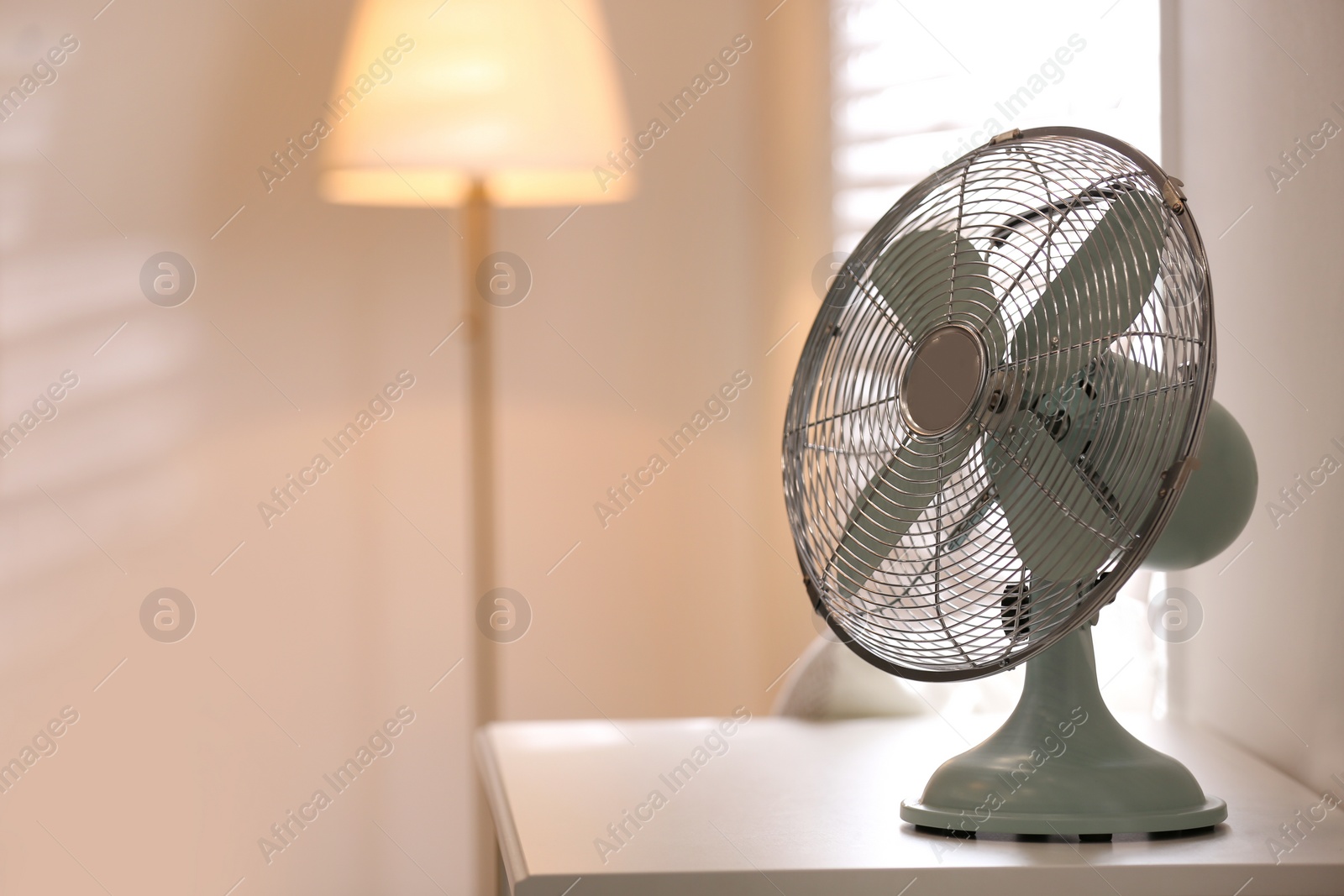 Photo of Modern electric fan on white table indoors. Space for text