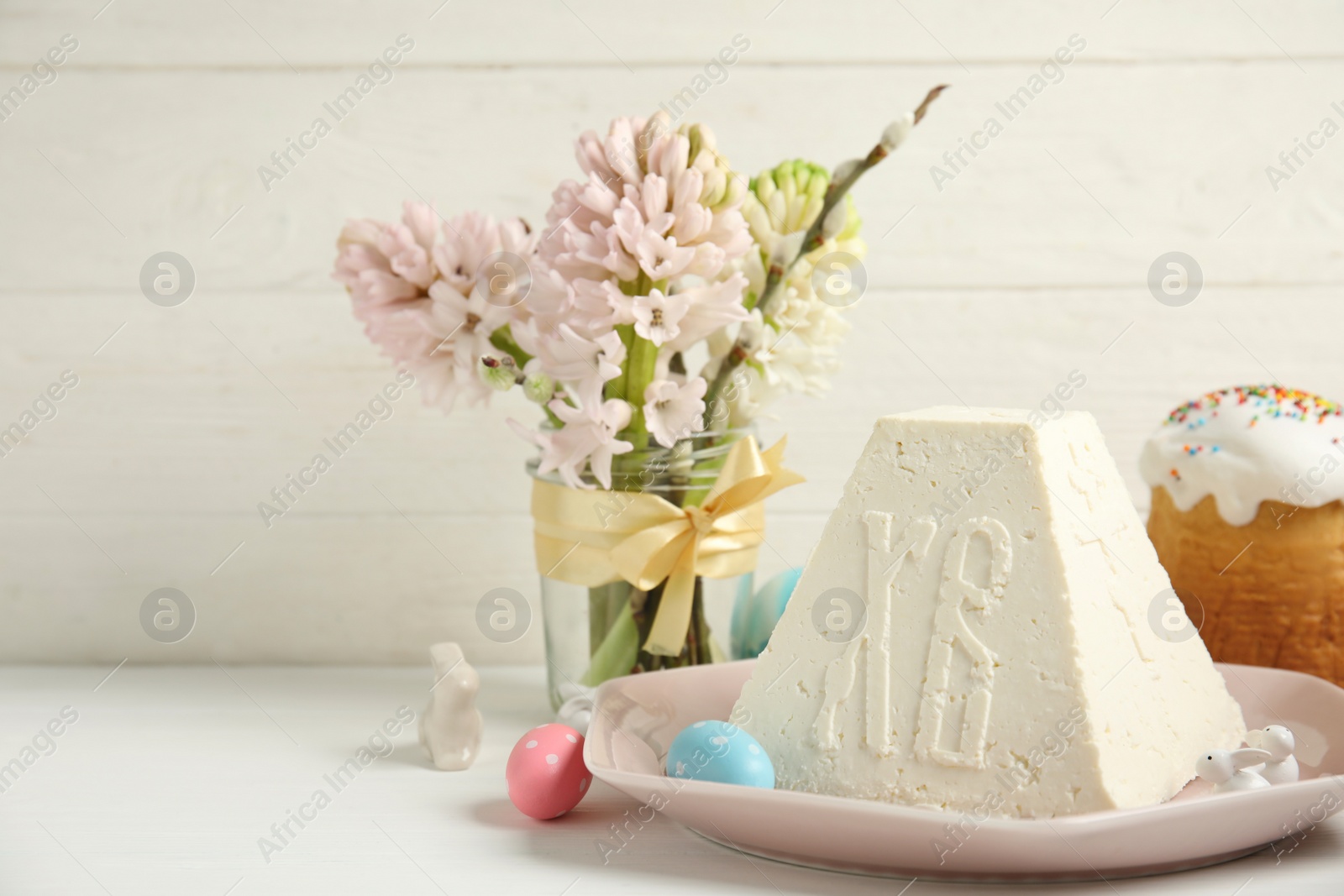 Photo of Traditional cottage cheese Easter paskha and eggs on white wooden table, space for text