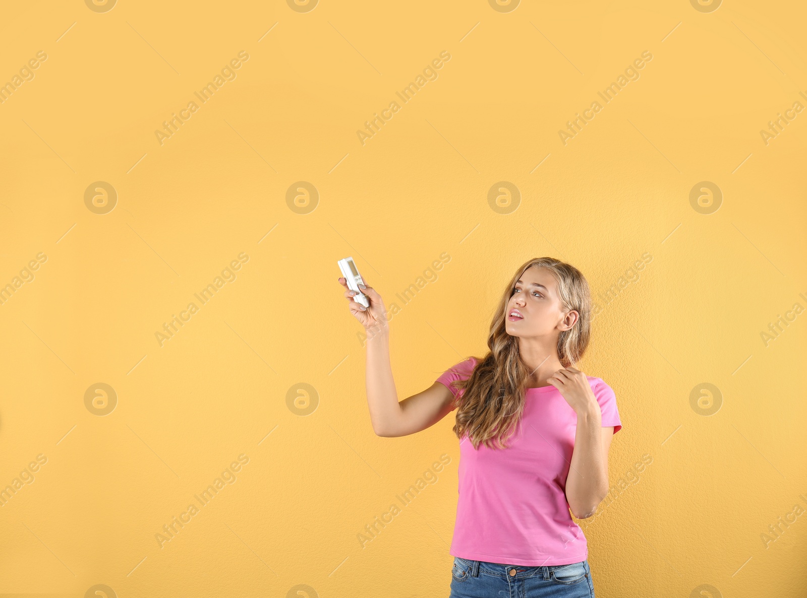 Photo of Young woman suffering from heat on color background. Air conditioner malfunction