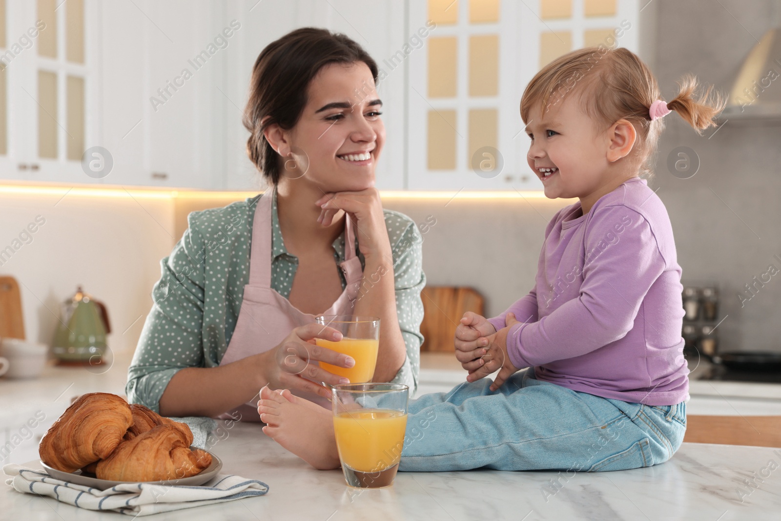 Photo of Mother and her little daughter having breakfast together in kitchen