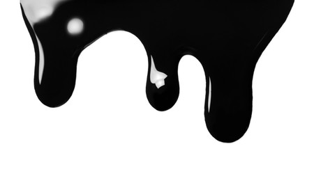 Photo of Black glossy oil flowing on white background