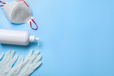 Photo of Medical gloves, respiratory mask and hand sanitizer on light blue background, above view. Space for text