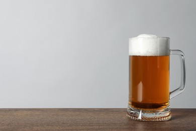 Photo of Mug of tasty beer on wooden table. Space for text