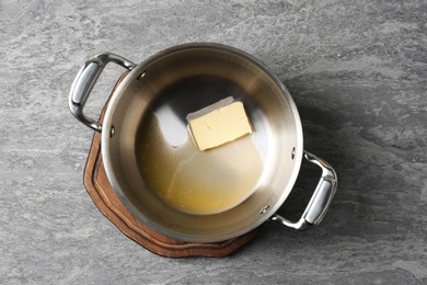 Photo of Pot with melting butter on grey background, top view