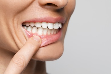 Woman showing healthy gums on light background, closeup. Space for text