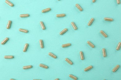 Photo of Many vitamin capsules on turquoise background, flat lay