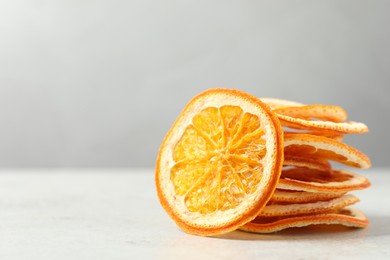 Stacked dry orange slices on white table, space for text