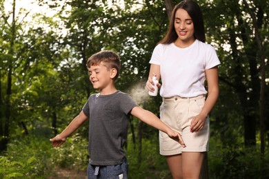 Photo of Woman applying insect repellent on her son's arm in park. Tick bites prevention