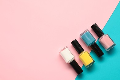 Bright nail polishes in bottles on color background, flat lay. Space for text