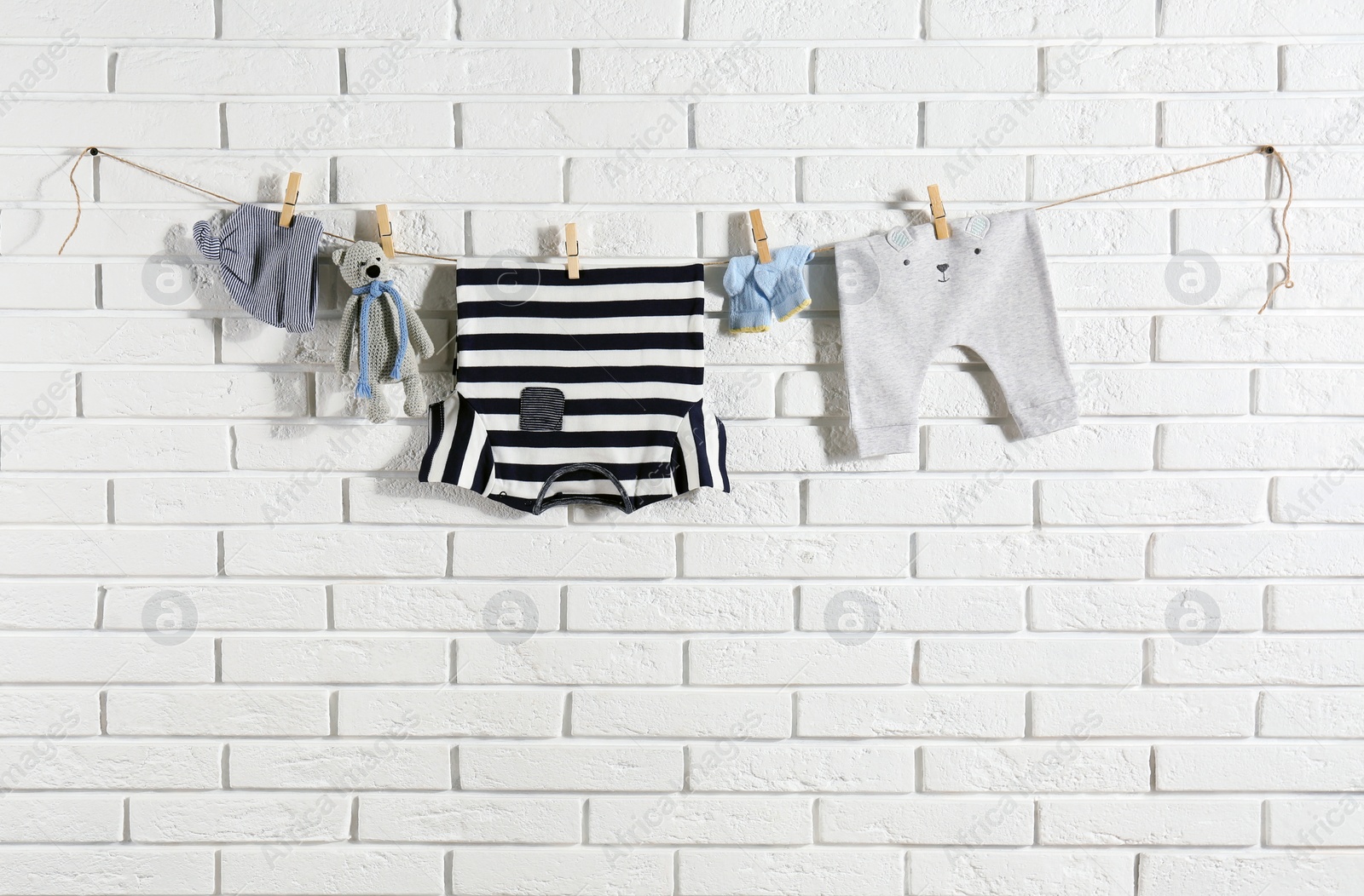 Photo of Baby clothes hanging on washing line near white brick wall