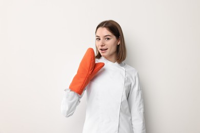 Photo of Professional chef with oven glove on light background
