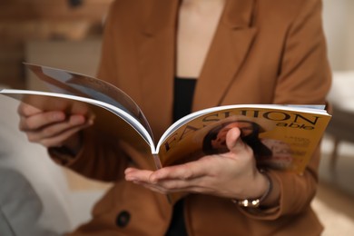 Woman reading fashion magazine at home, closeup