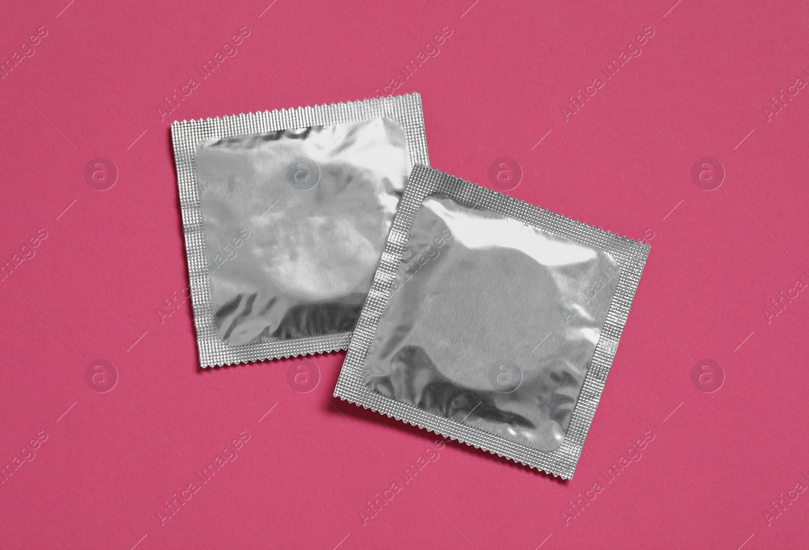 Photo of Condom packages on pink background, flat lay. Safe sex