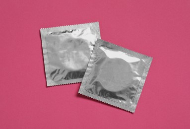 Photo of Condom packages on pink background, flat lay. Safe sex