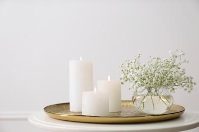 Photo of Vase with beautiful flowers and burning candles on table indoors. Interior elements