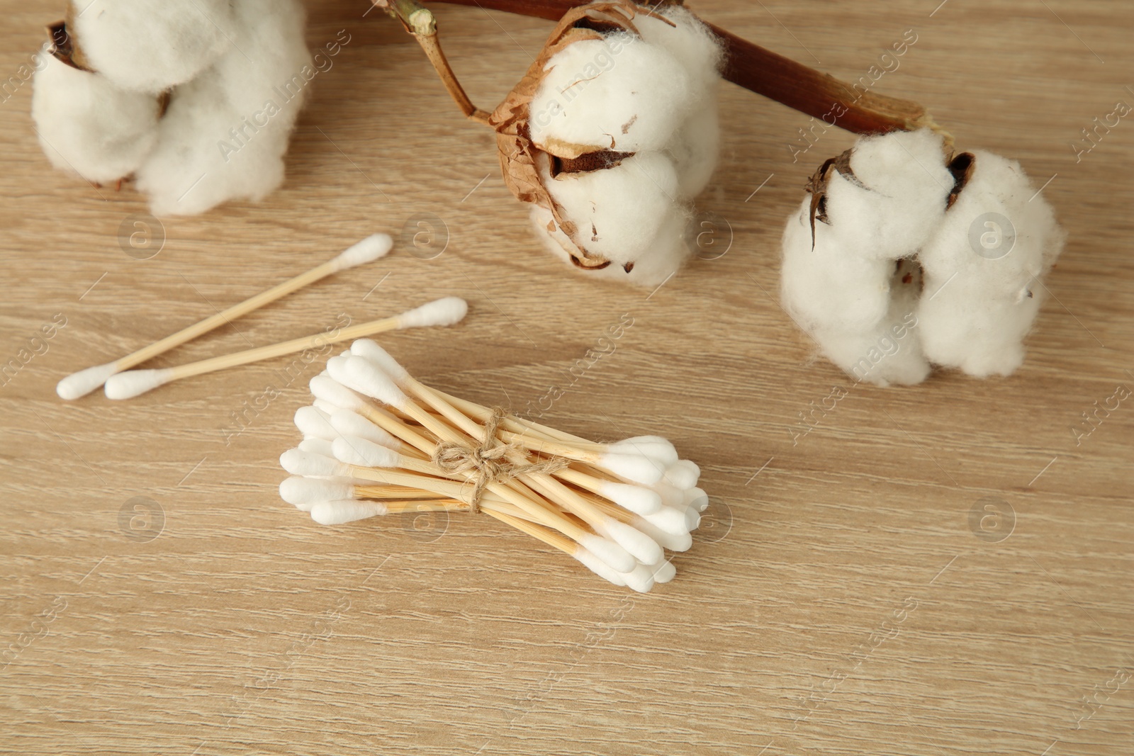 Photo of Cotton swabs and flowers on wooden table, closeup