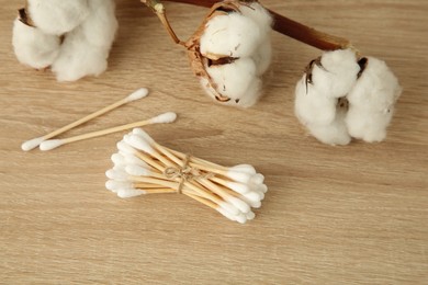 Photo of Cotton swabs and flowers on wooden table, closeup