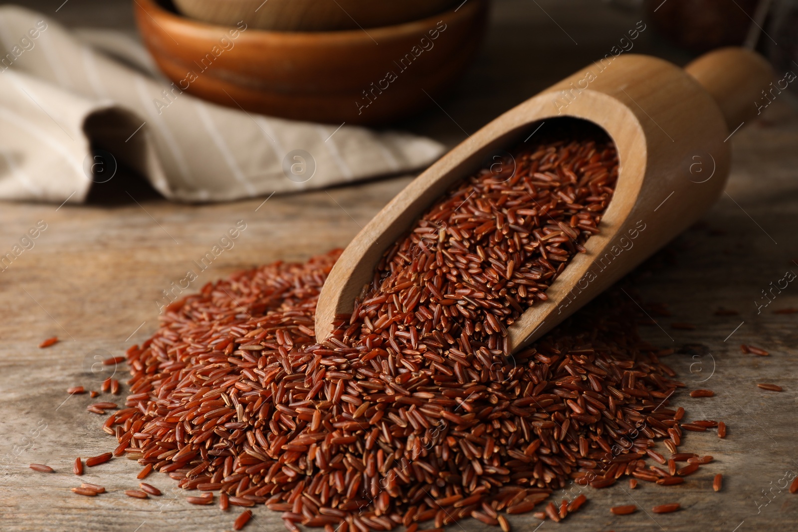 Photo of Brown rice in wooden scoop on table