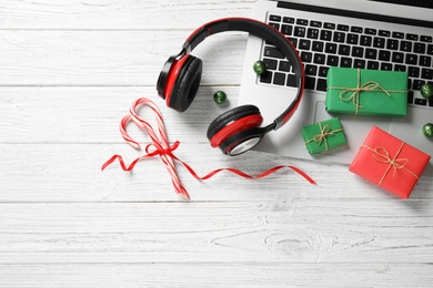 Flat lay composition with headphones on white wooden background, space for text. Christmas music concept