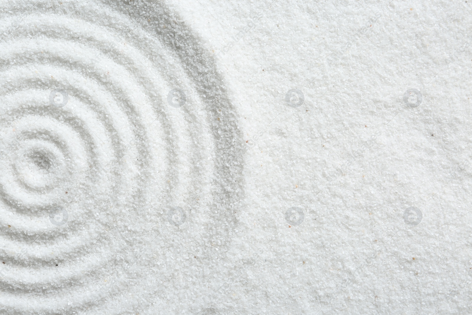 Photo of Zen rock garden. Circle pattern on white sand, top view. Space for text