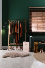 Photo of Modern dressing room interior with clothing rack and comfortable sofa
