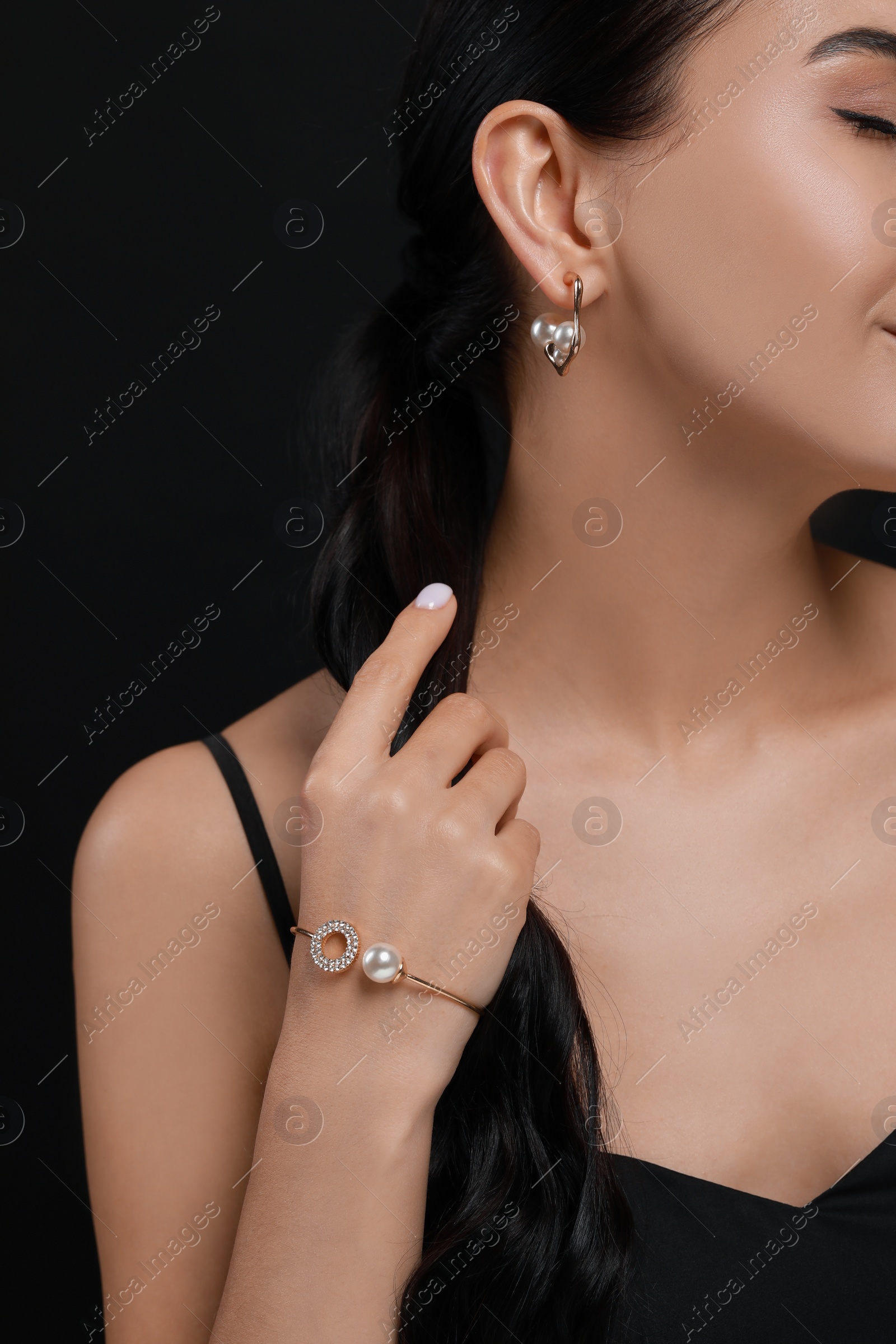 Photo of Young woman with elegant pearl jewelry on black background, closeup