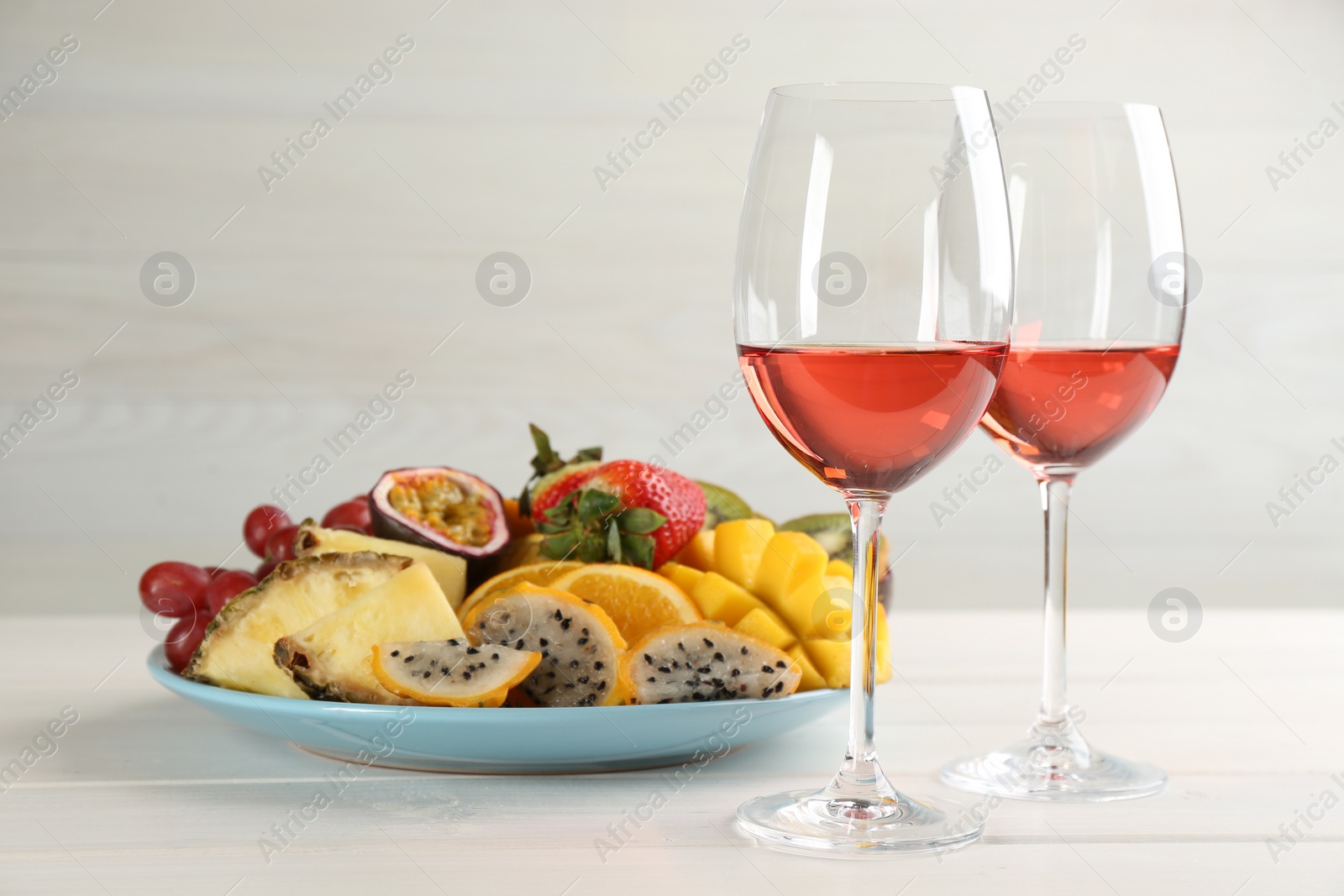 Photo of Delicious exotic fruits and glasses of wine on white wooden table