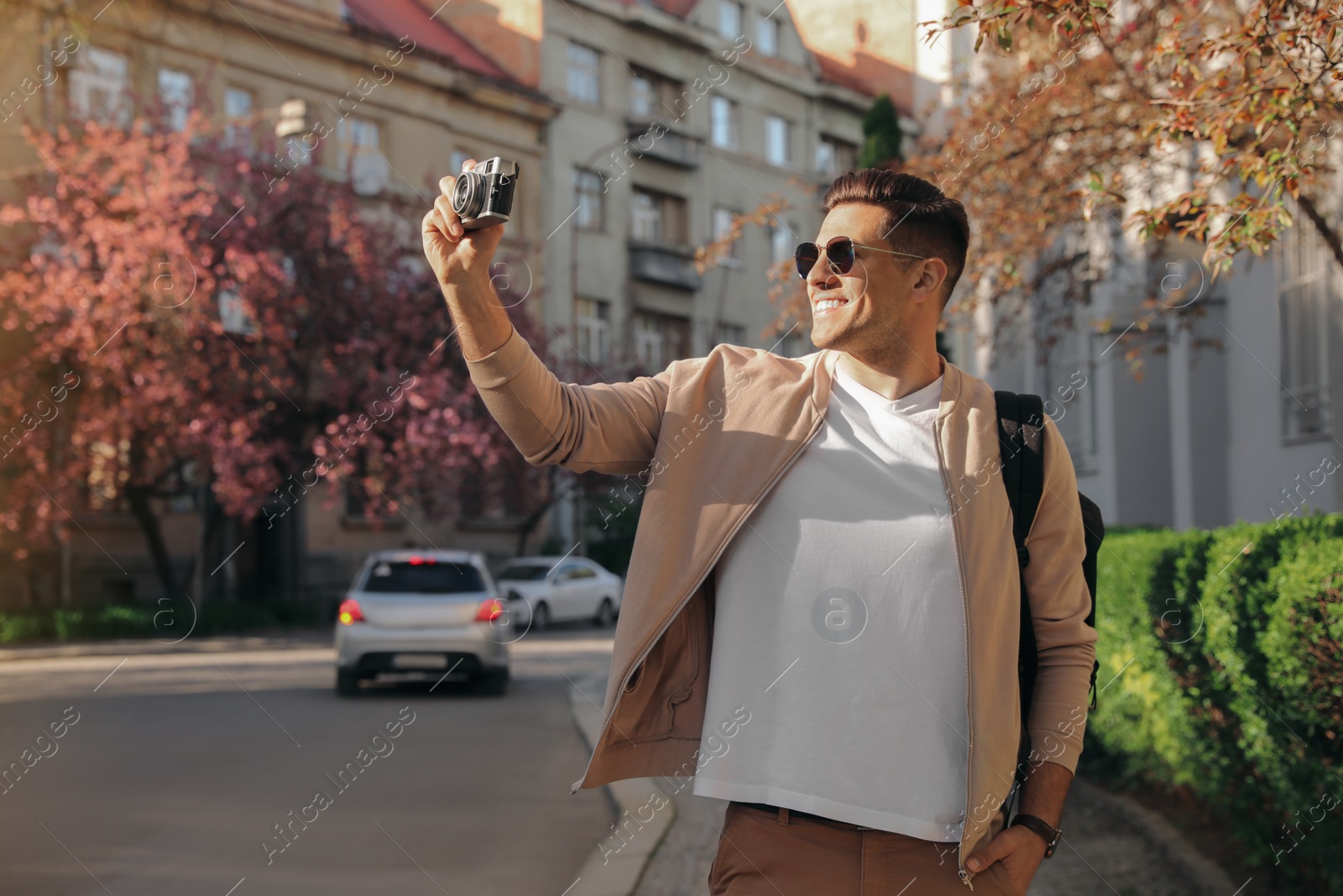 Photo of Happy male tourist with camera on city street