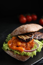Photo of Delicious eggplant sandwich on slate board, closeup