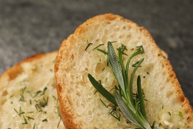 Tasty baguette with garlic, rosemary and dill on table, closeup