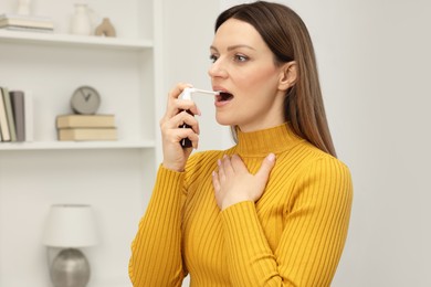 Photo of Adult woman using throat spray at home, space for text