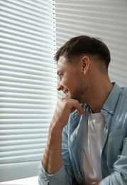 Handsome man near window with Venetian blinds