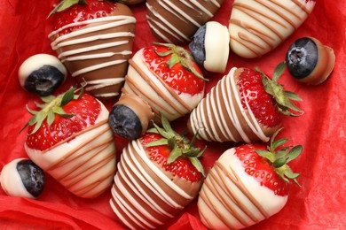 Photo of Delicious chocolate covered strawberries and blueberries in box, top view