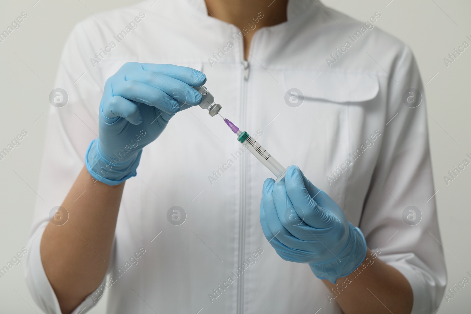Photo of Doctor filling syringe with hepatitis vaccine from glass vial on grey background, closeup