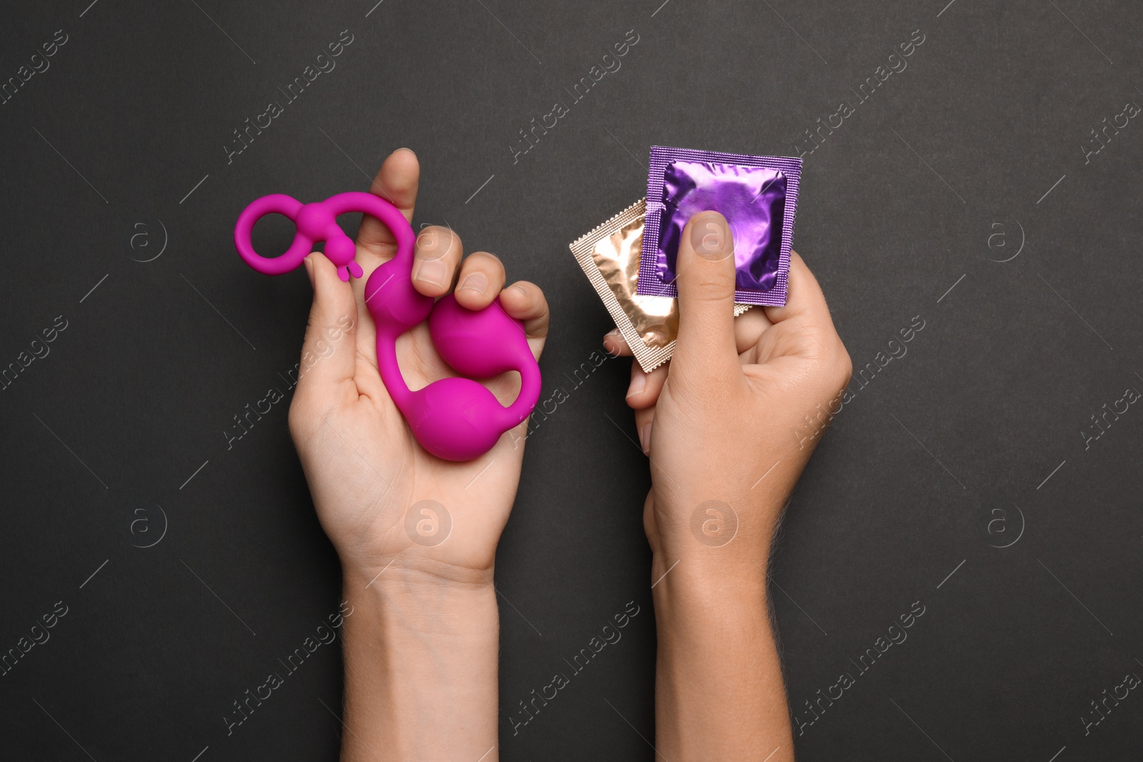 Photo of Woman with anal balls beads and condoms on black background, top view. Sex game