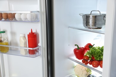 Photo of Modern open refrigerator full of different products