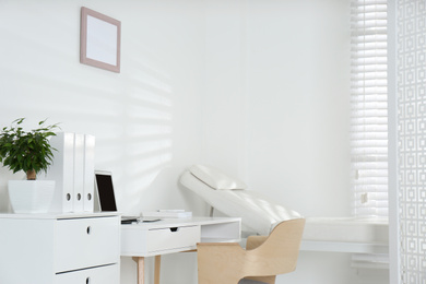 Photo of Doctor's office interior with examination couch and desk