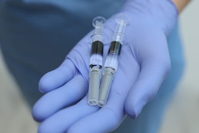 Photo of Doctor holding syringes with COVID-19 vaccine, closeup