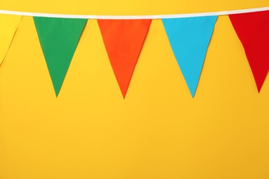 Bunting with colorful triangular flags on orange background, space for text