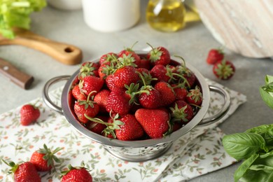 Photo of Metal colander with fresh strawberries on grey table