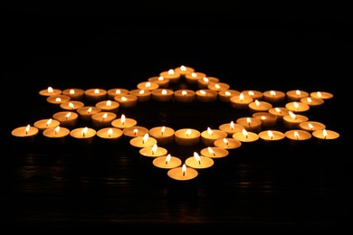 Photo of Star of David made with burning candles on black background. Memory day